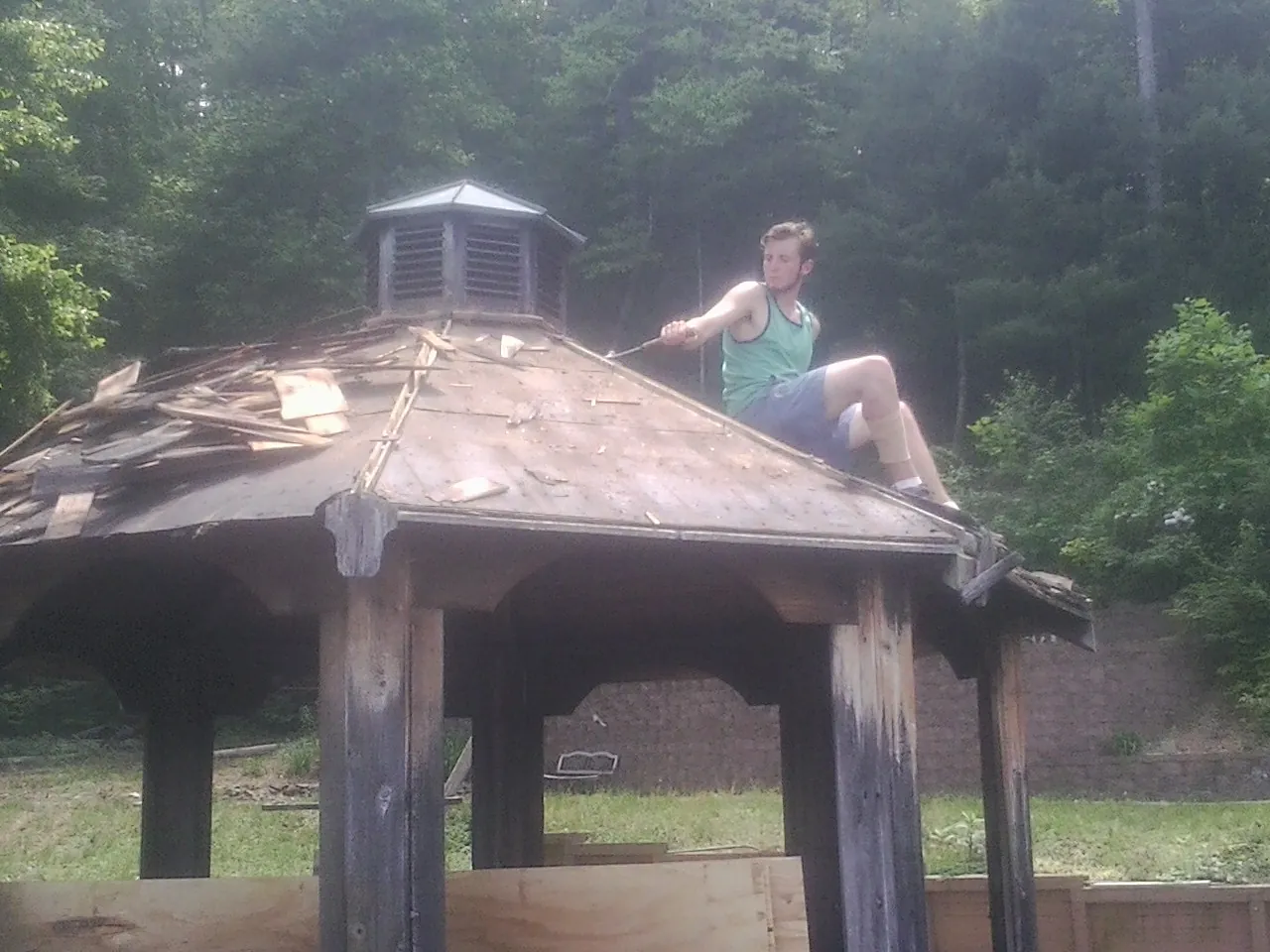 Tearing the old roof off a wooden gazebo before new shakes in Emerado