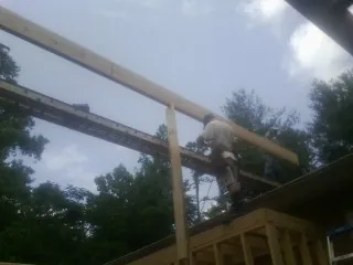 Carpenter setting a ridge beam over a new addition frame — Ice Dam Removal by Roofing Brothers in Emerado