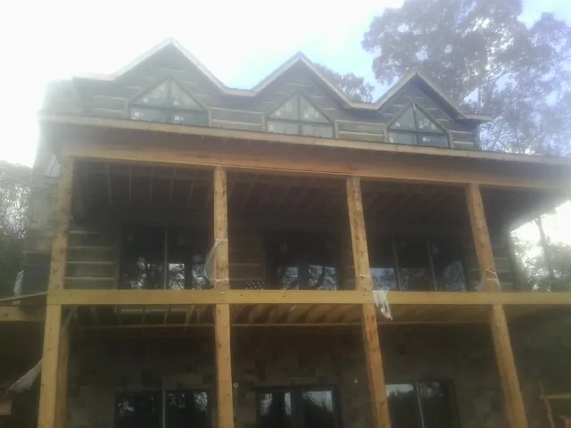 Dormers and porch framing on a large log home under construction — Roof Coating work by our crew in Emerado