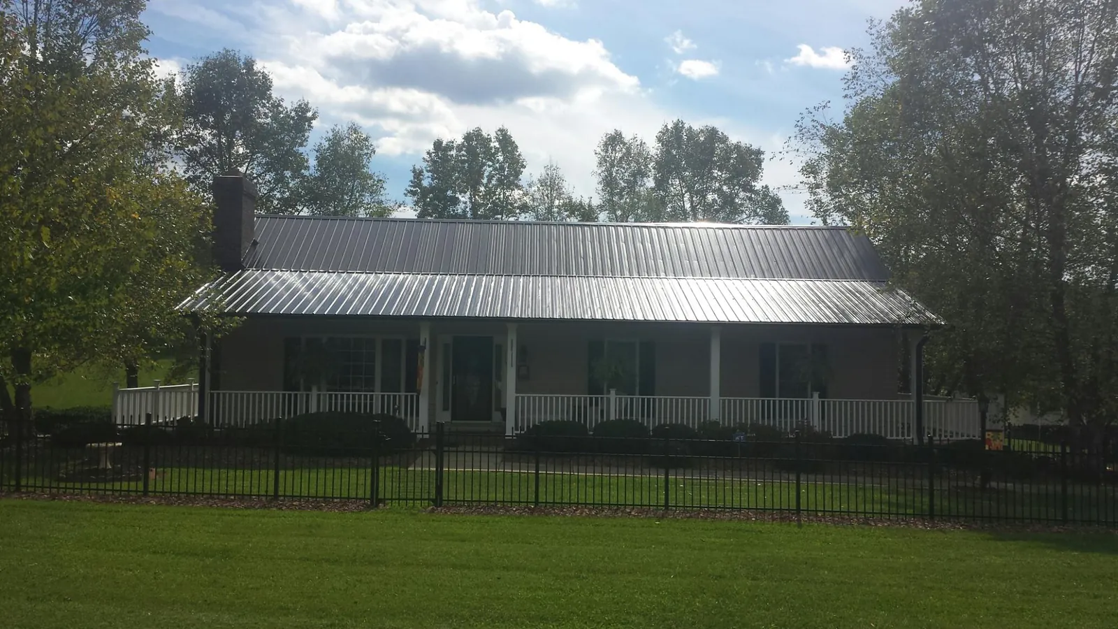 Gray metal roof on a brick ranch with a full width front porch — Gutter Guard Installation work by our crew in Emerado