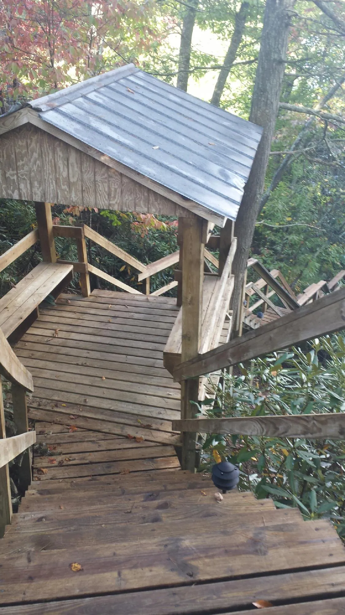 Metal roofed shelter over wooden steps on a wooded walkway — Skylight Repair & Installation work by our crew in Emerado