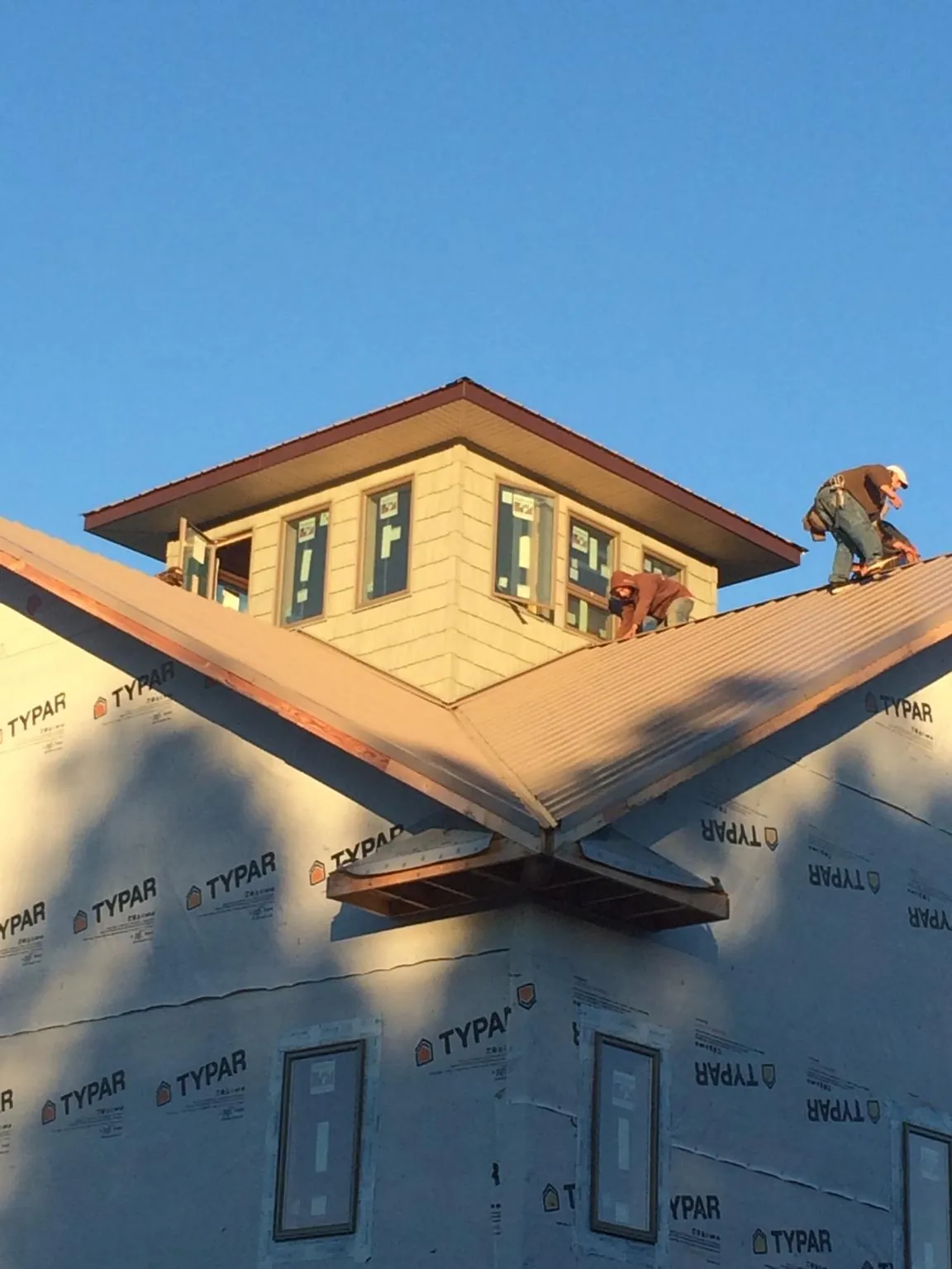 Roofers working around a rooftop cupola on a new metal roof at sunset — Roof Waterproofing in Emerado by Roofing Brothers